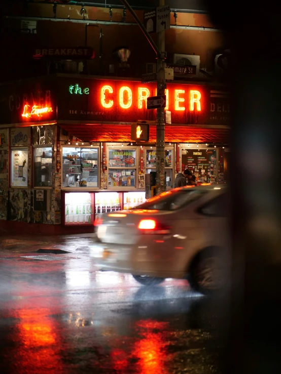 a car is driving past a diner on a rainy night