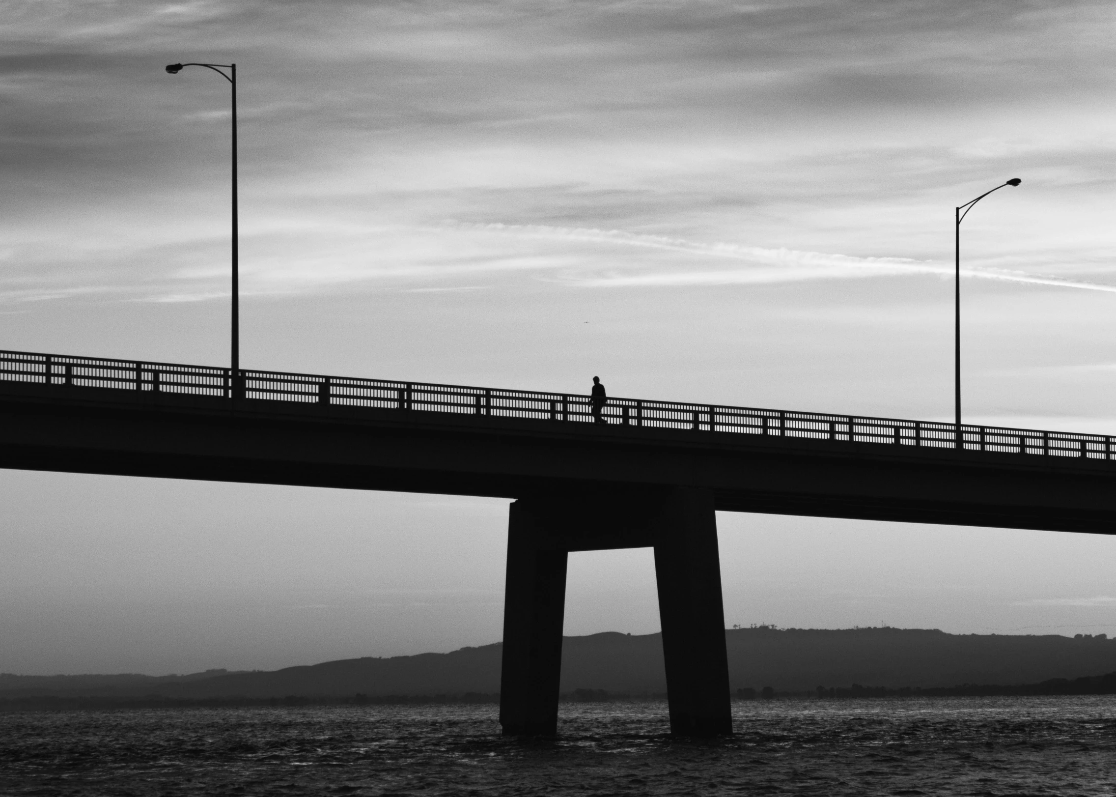 a bridge that is over looking water and cloudy sky