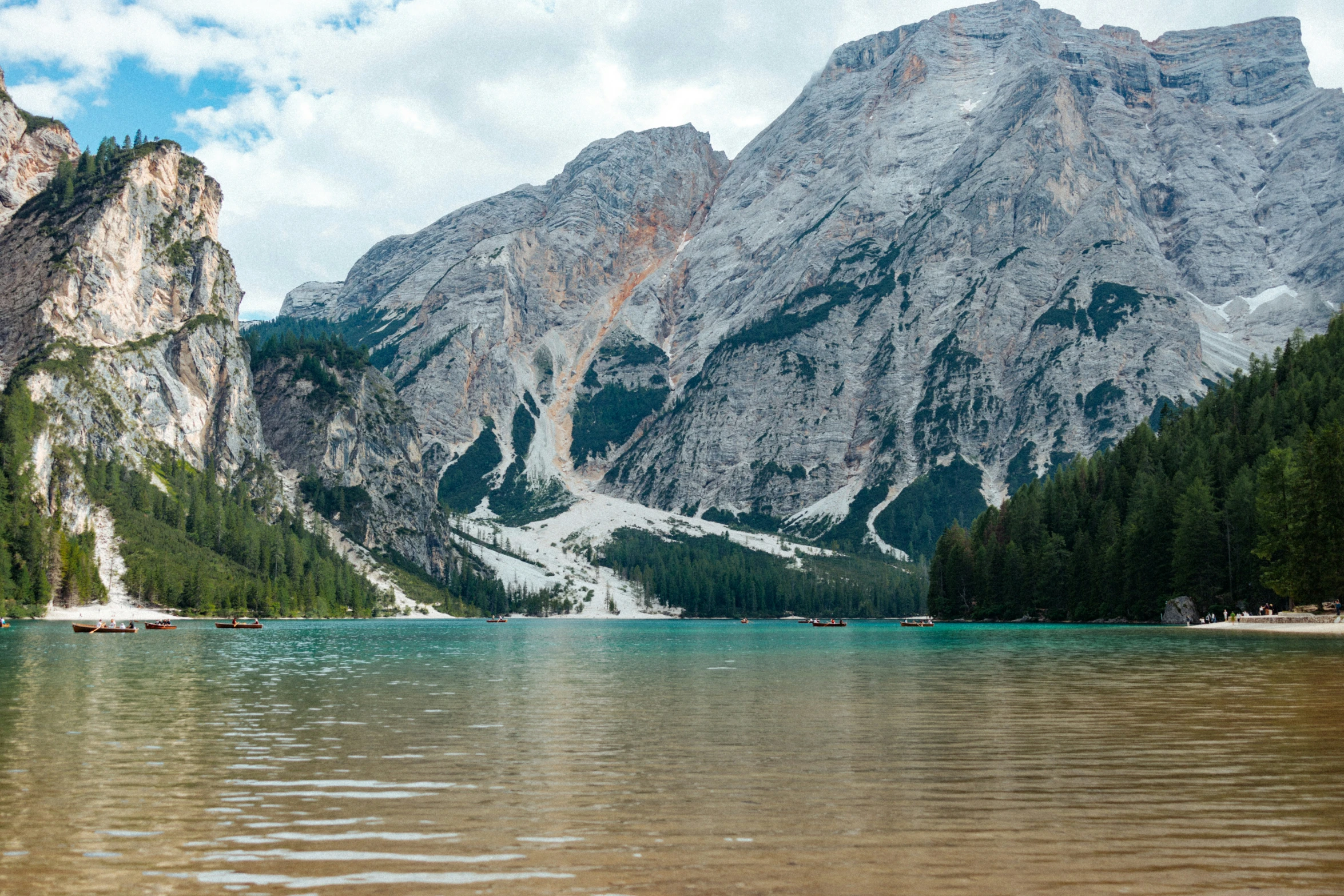 the mountain is covered with snow near the clear lake