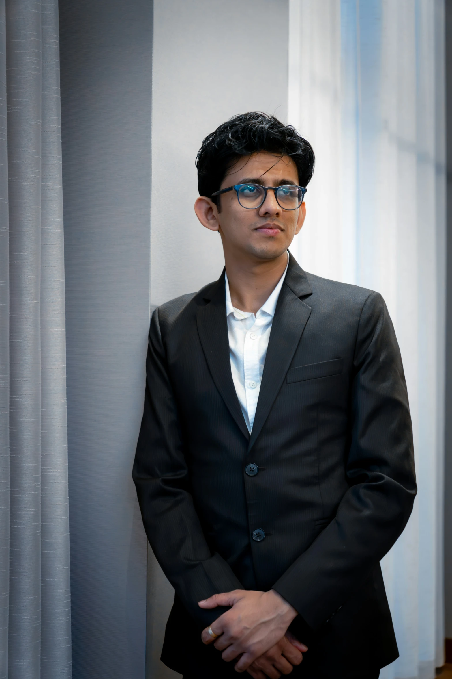 a man is standing in a suit with glasses on his head