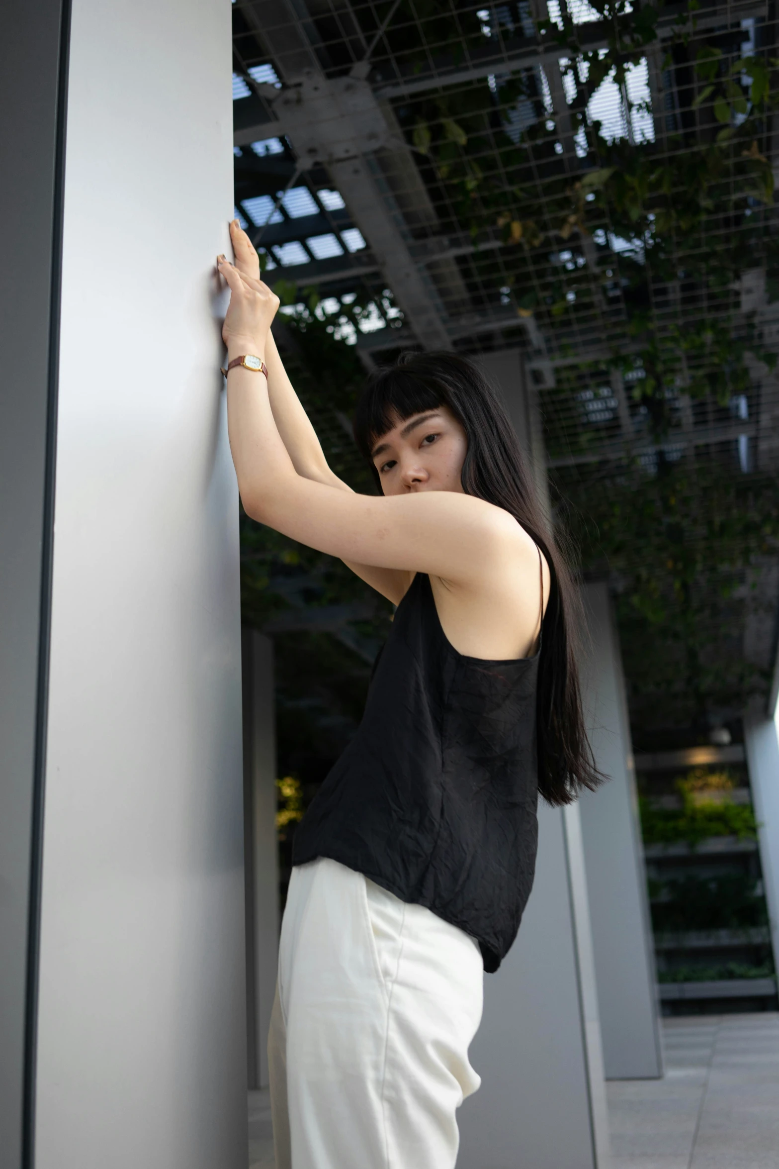 woman standing and leaning against a wall holding on to it