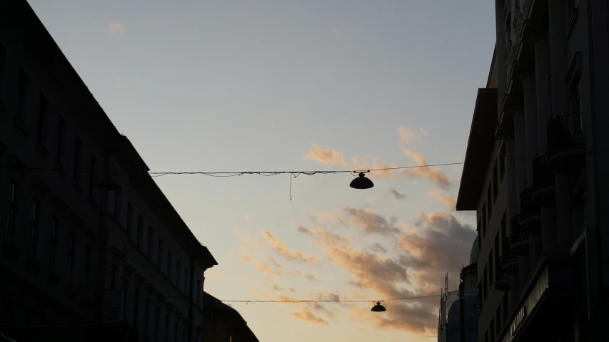 two lights hang on a wire in an alley