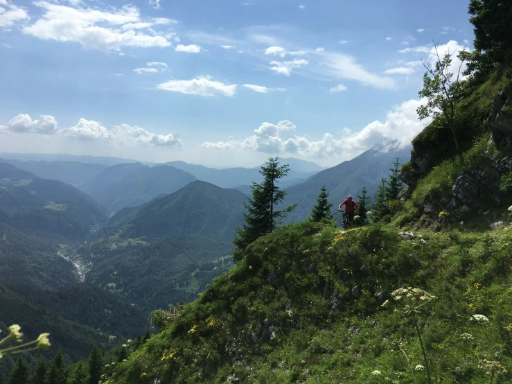 two hikers walking along the grassy side of a mountain