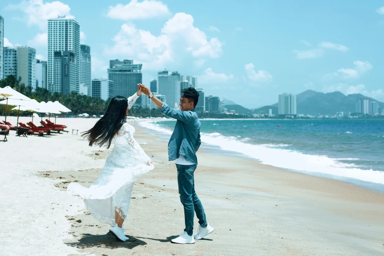 the young couple are dancing on the beach