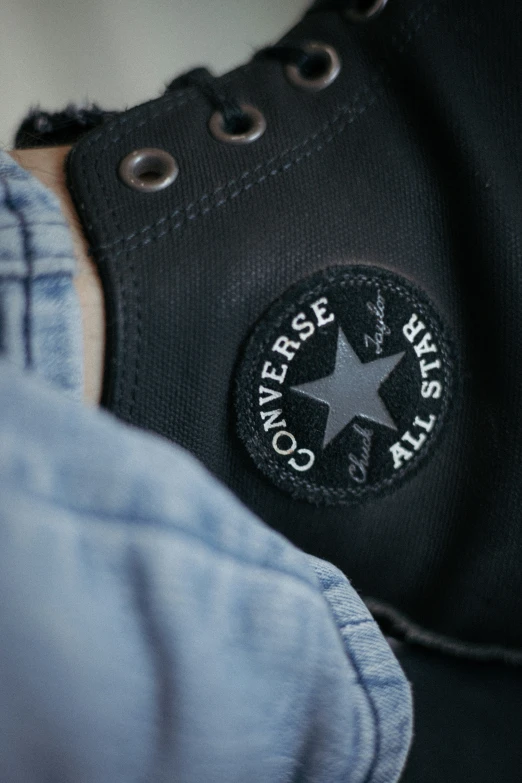 a person wearing black converse sneakers with black star on the bottom