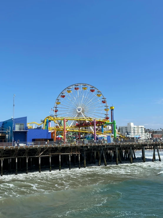 a carnival on a pier with water and buildings in the background