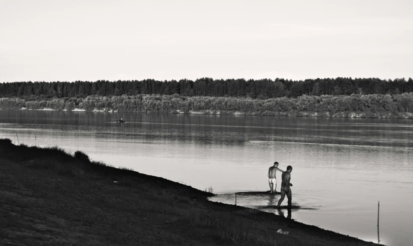 the two people stand on a dock on the shore near the lake