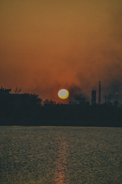 the setting sun in the sky over a lake