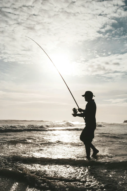 a man stands at the edge of the water with his fishing rod