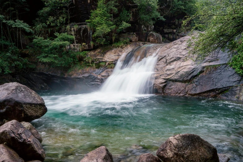 small waterfall on the edge of rock - strewn river in forest