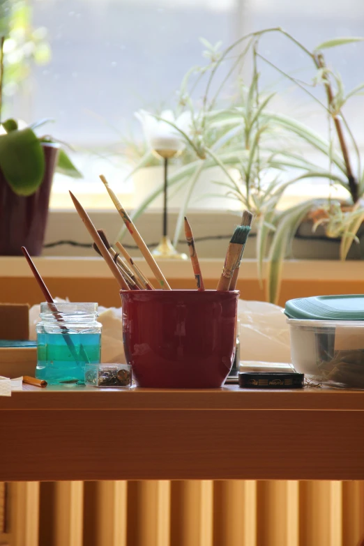 several different paints and brushes in a red bowl