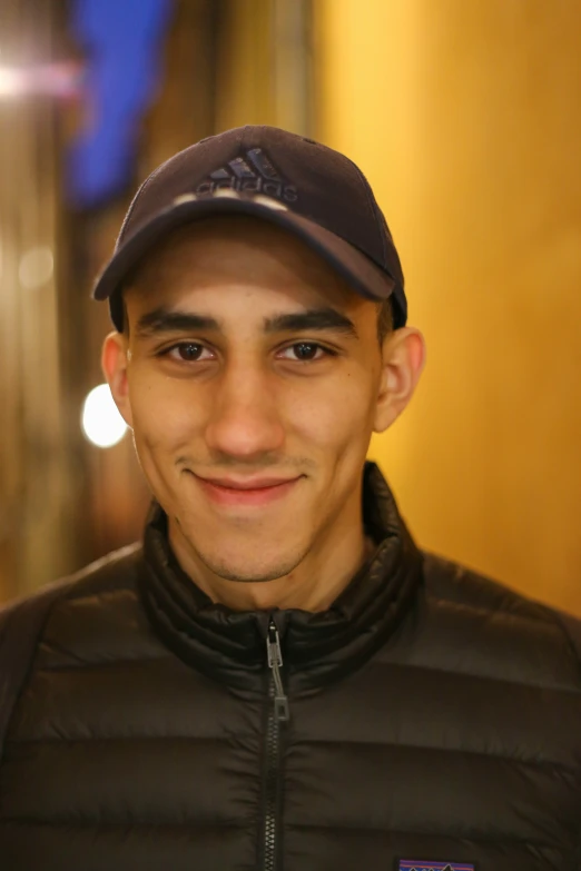 man in jacket and cap smiling for po