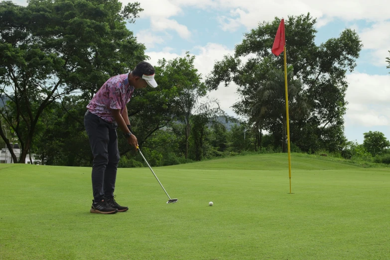 the golf player is putting his club at the hole