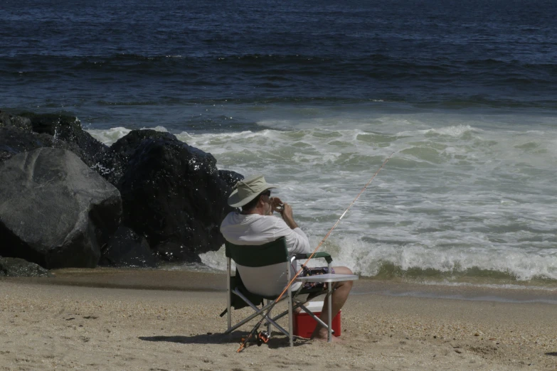 a man on the beach is sitting in a chair fishing