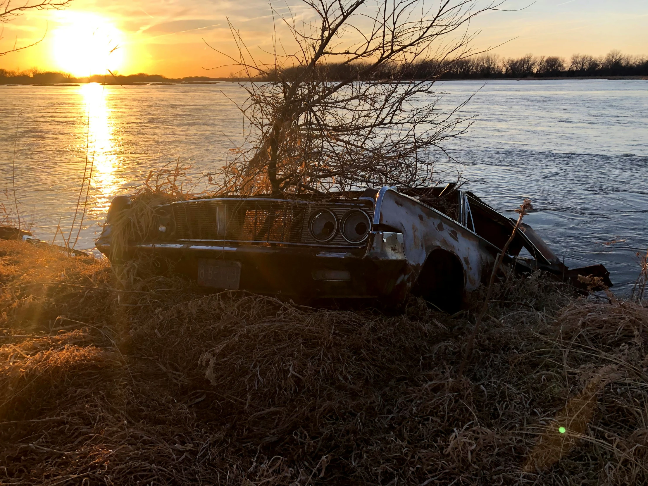 the truck is parked by the lake and the sun is setting