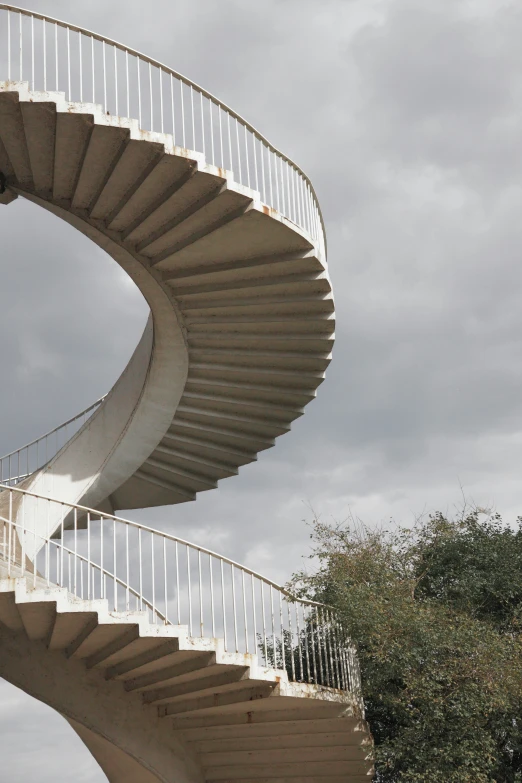 the spiral stairs of an abstract building next to trees