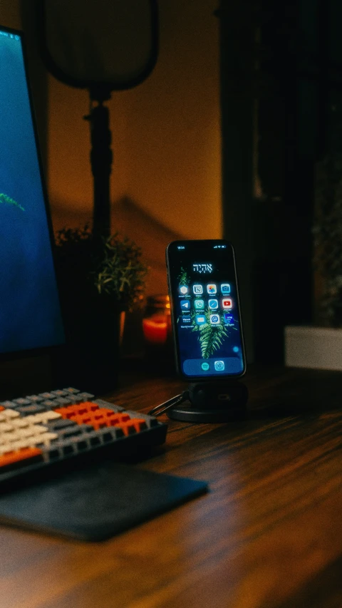 an iphone is on a desk beside a remote control and the other side is next to the computer monitor