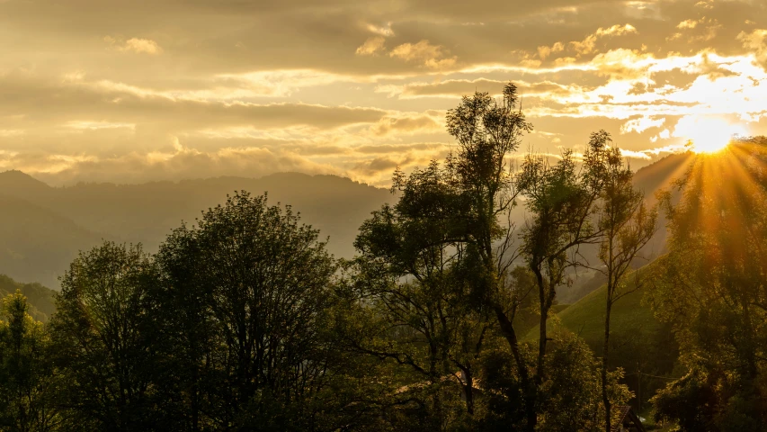 a sunset in the mountains with the sun breaking through the clouds