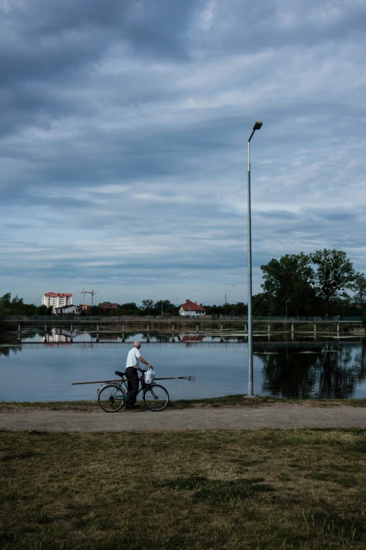 man with bicycle looking over railing into water