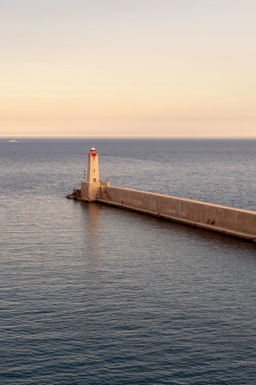 a long light house sitting on the end of a concrete pier