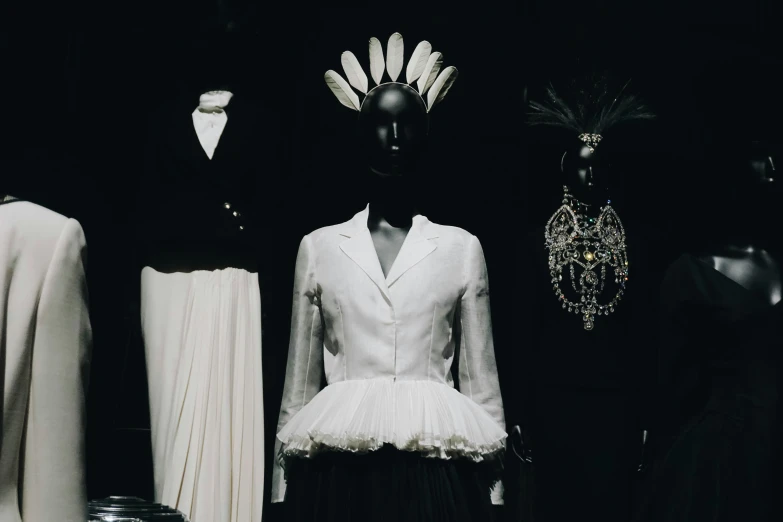 a man and two women are in front of mannequins wearing gowns