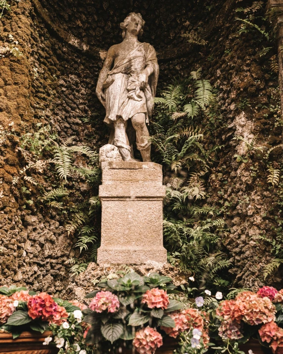 a statue surrounded by many flowers outside