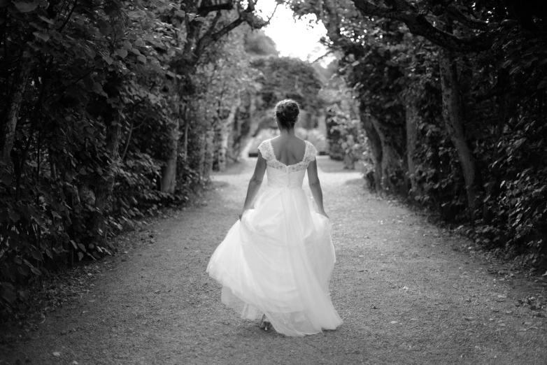 a woman in a dress is walking down a path