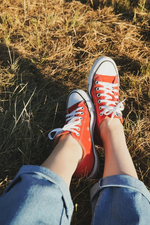 a woman wearing orange sneakers standing on top of grass