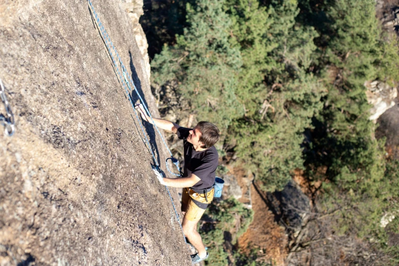 a man in black shirt and yellow shorts on a rock