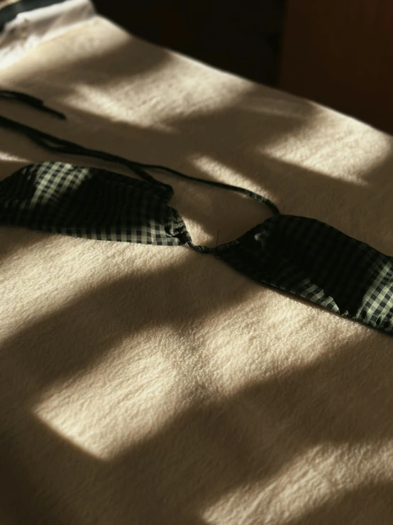 a black and white plaid tie on the white blanket