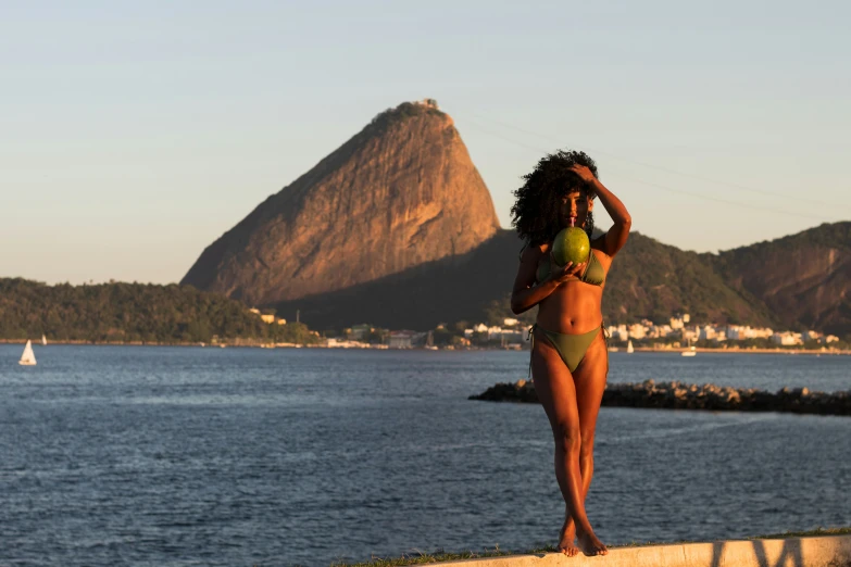 woman with full body bikini standing on beach next to large mountains