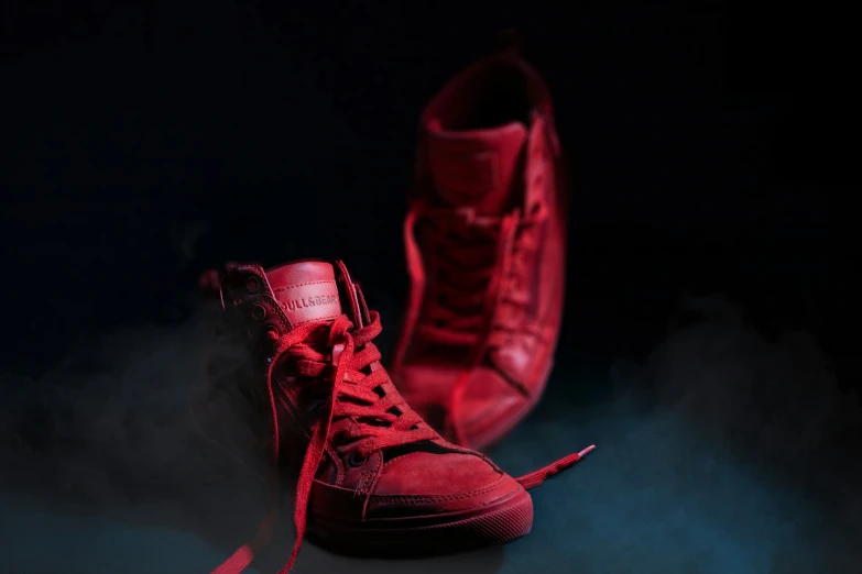 a pair of red high - top shoes, sitting on a black background