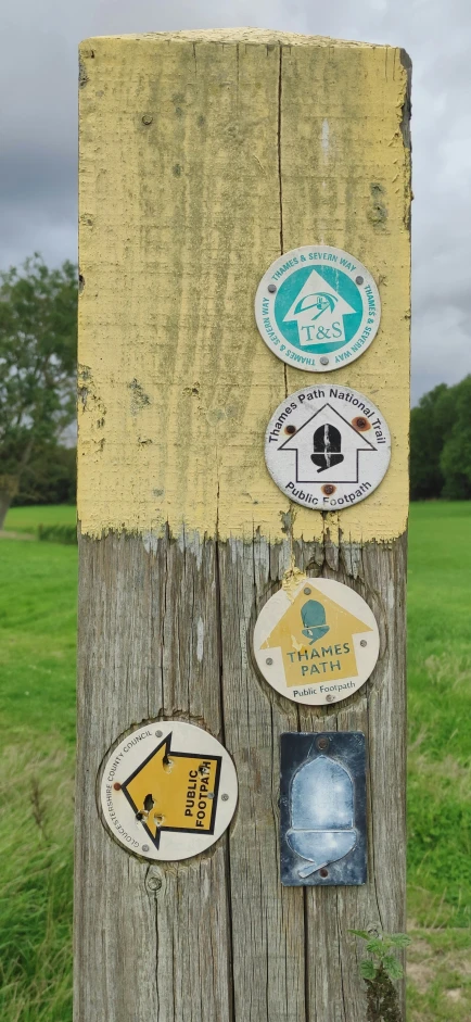 there is a wooden post with a bunch of signs on it