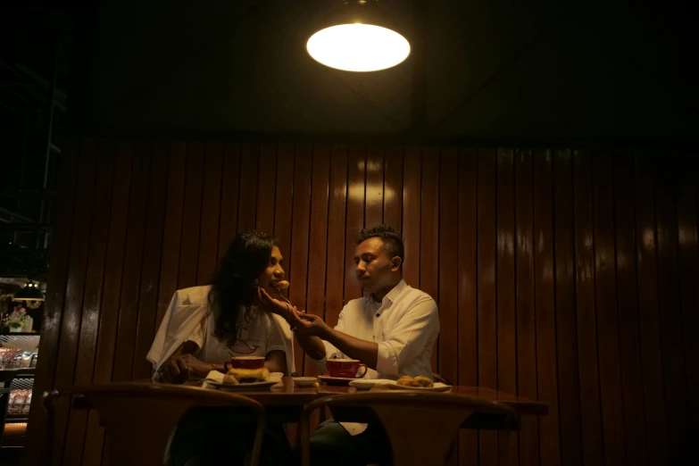 two people sitting down next to each other at a table