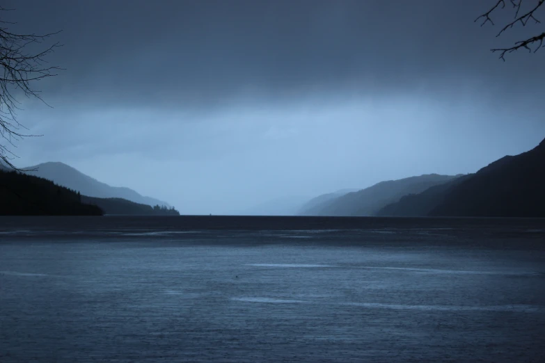 an overcast day at a lake with a lone boat