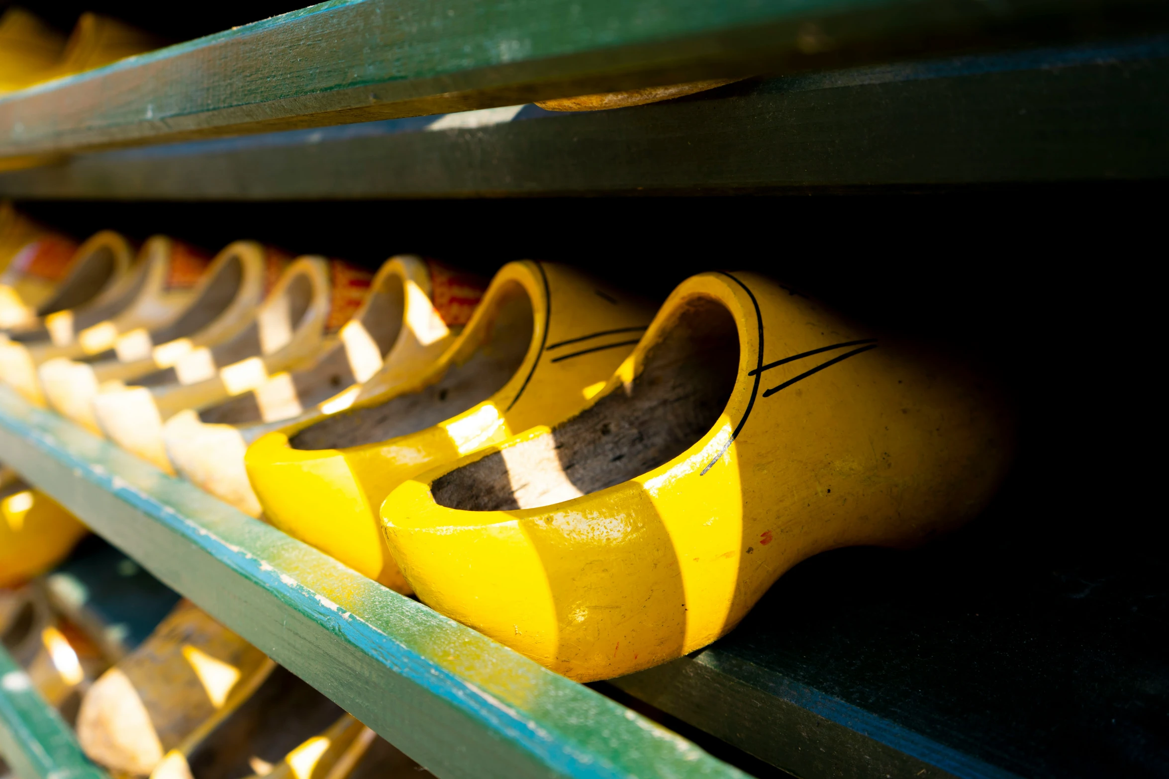 many pairs of rubber shoes lined up on some shelves