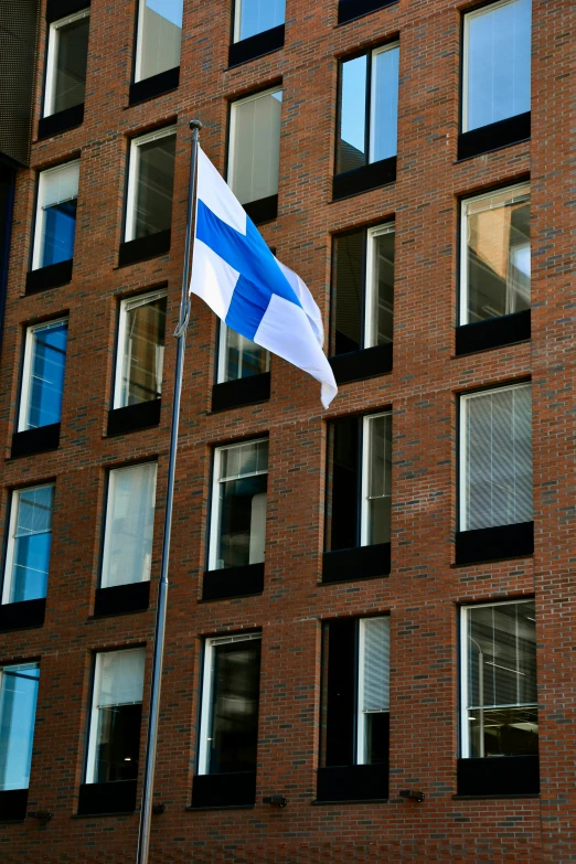 a blue and white flag in front of a tall building