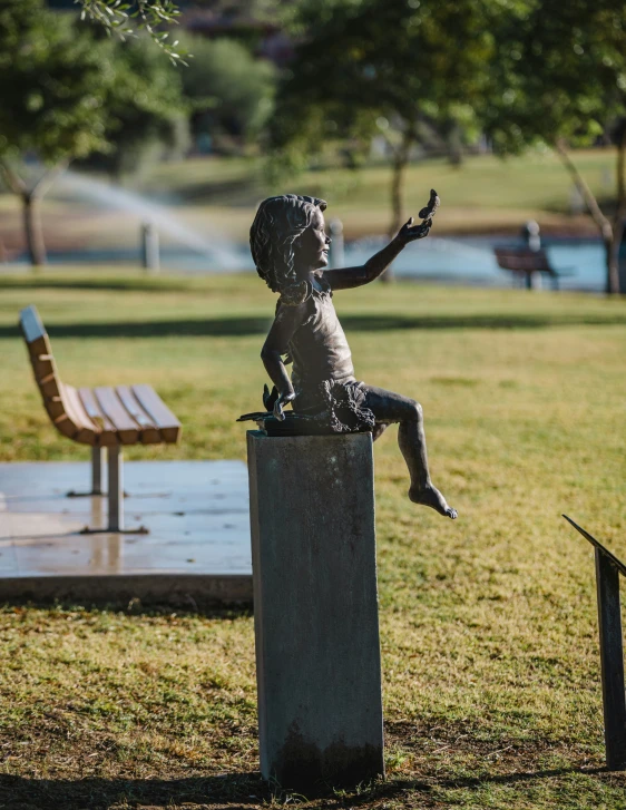 a little statue of a boy sitting on a pillar