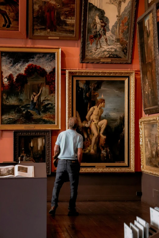 a man looking at the paintings in a room