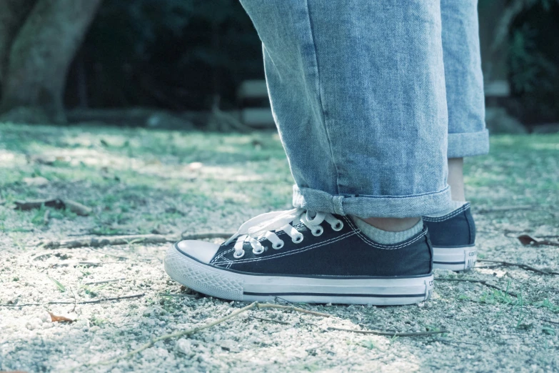 a person is wearing jeans and shoes with black and white sneakers