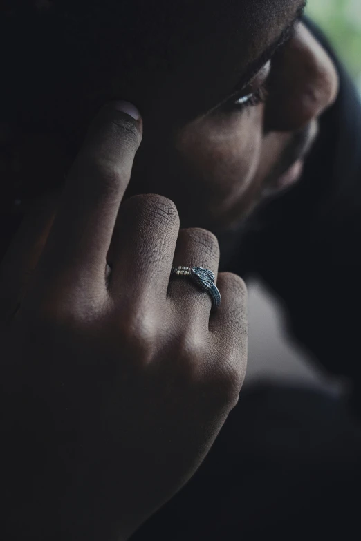 a person wearing a silver ring holding his hand near his face