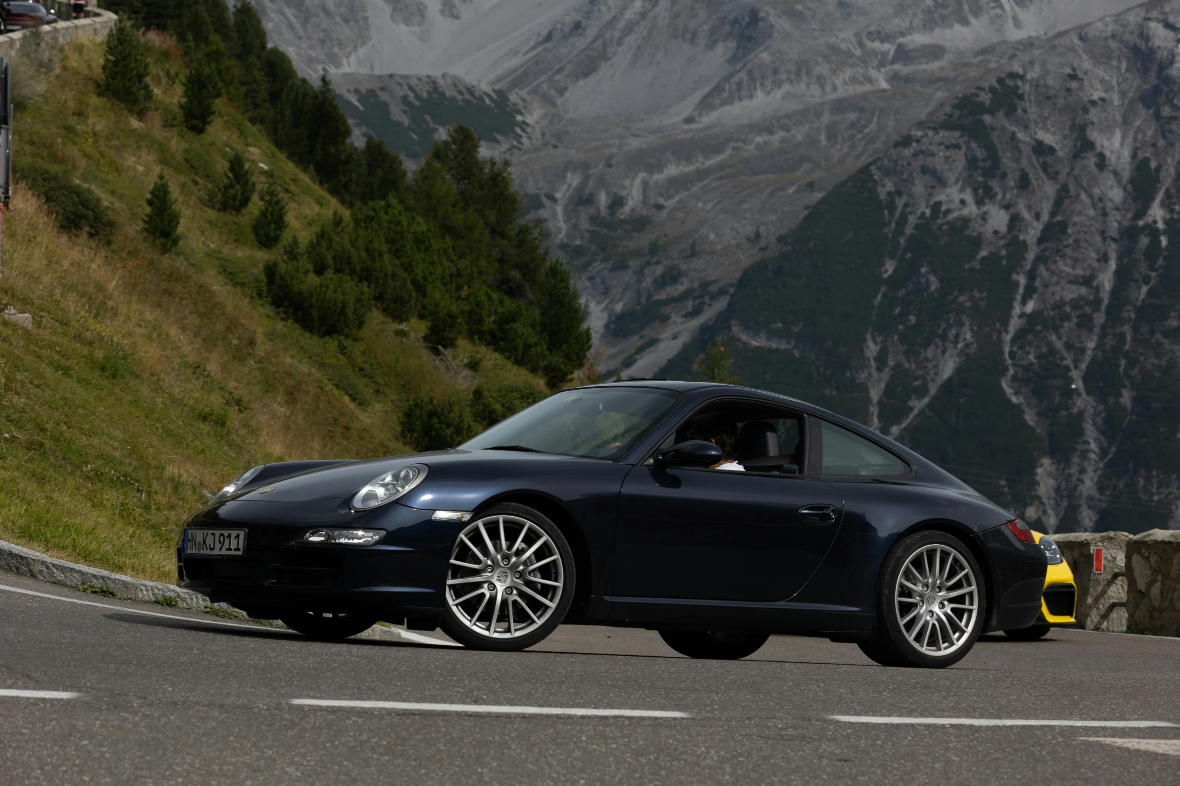 a black porsche sports car on the side of a mountain