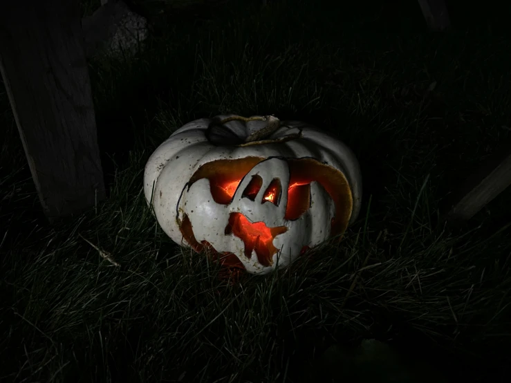 a pumpkin sitting in the grass on a halloween day