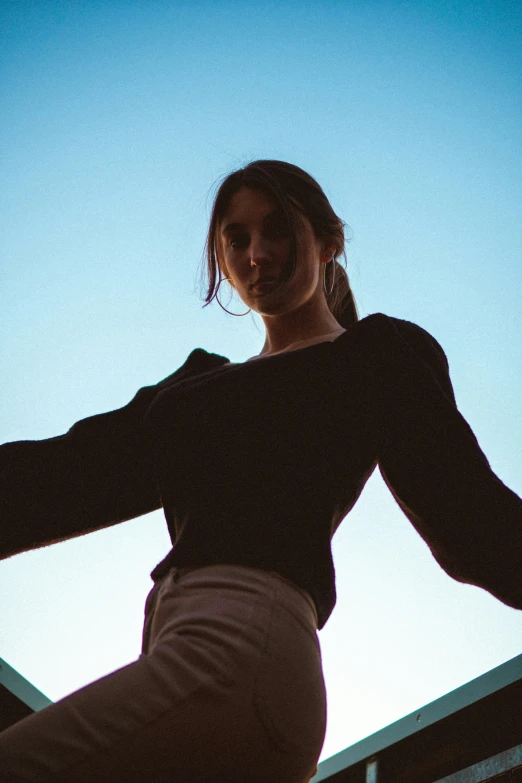 silhouette of a girl standing with one arm outstretched to her chest