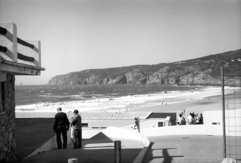 people on a beach near the water watching soing