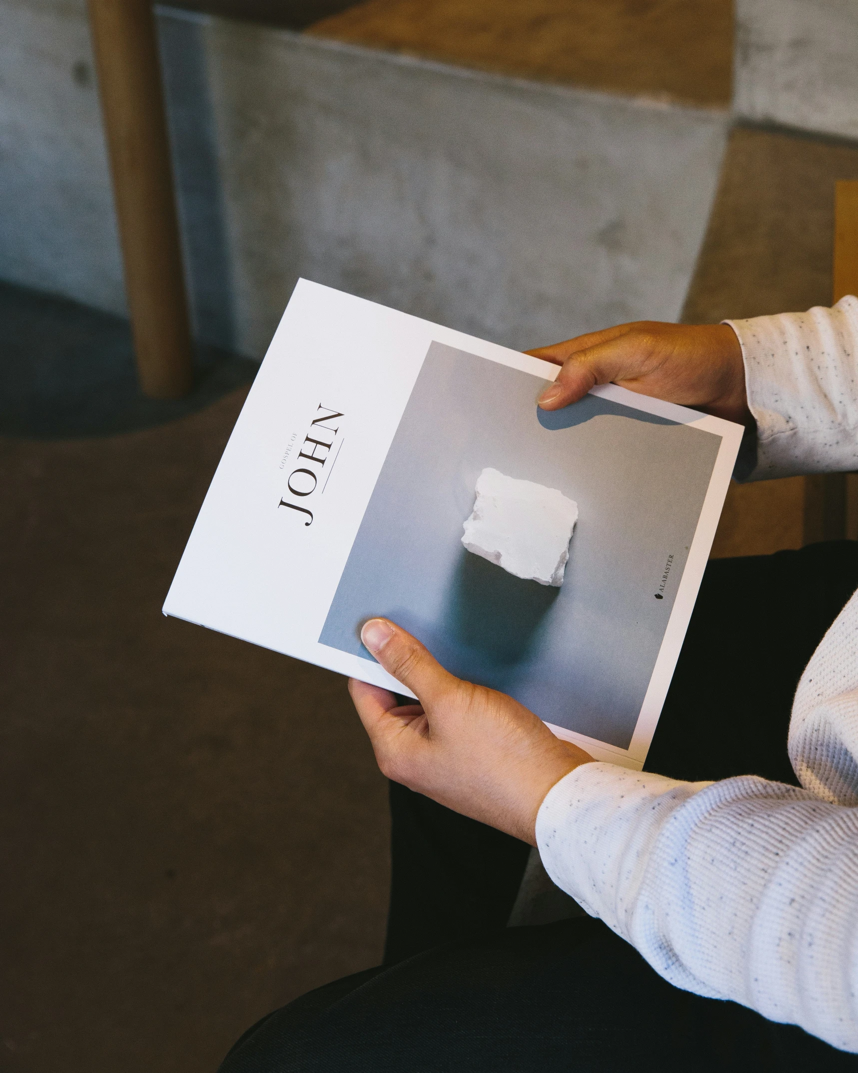 someone holding up a book with an image of a picture of a table