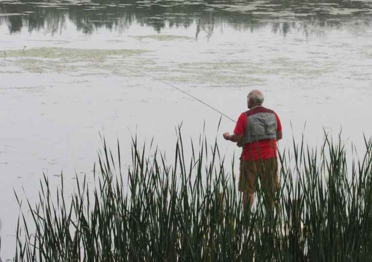 an elderly man fishing in the lake with a stick