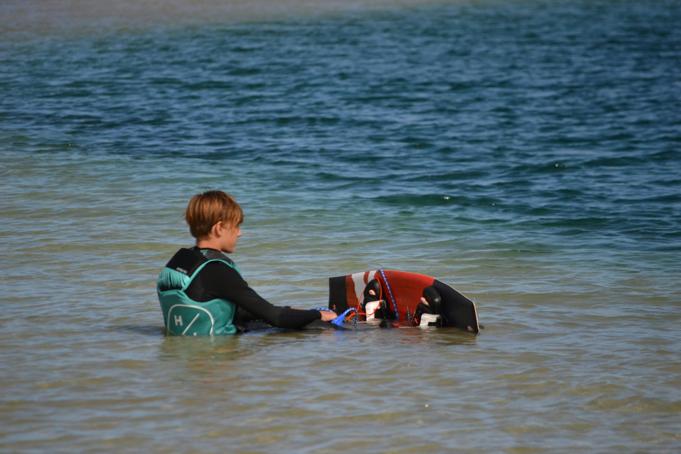 a  sits in the shallow water with his dog