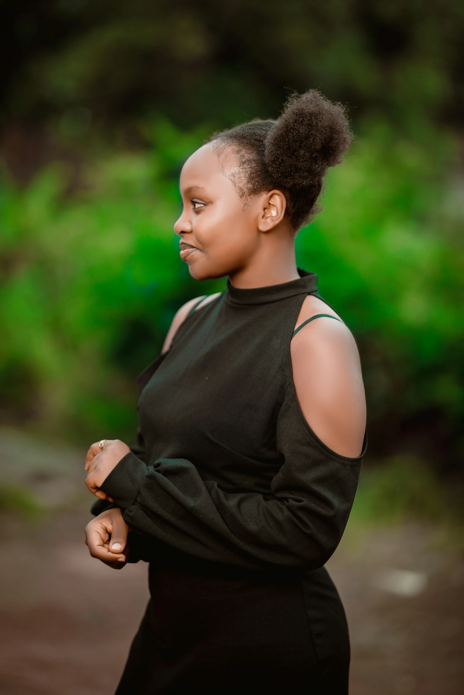 a woman in a black dress standing with her arms folded