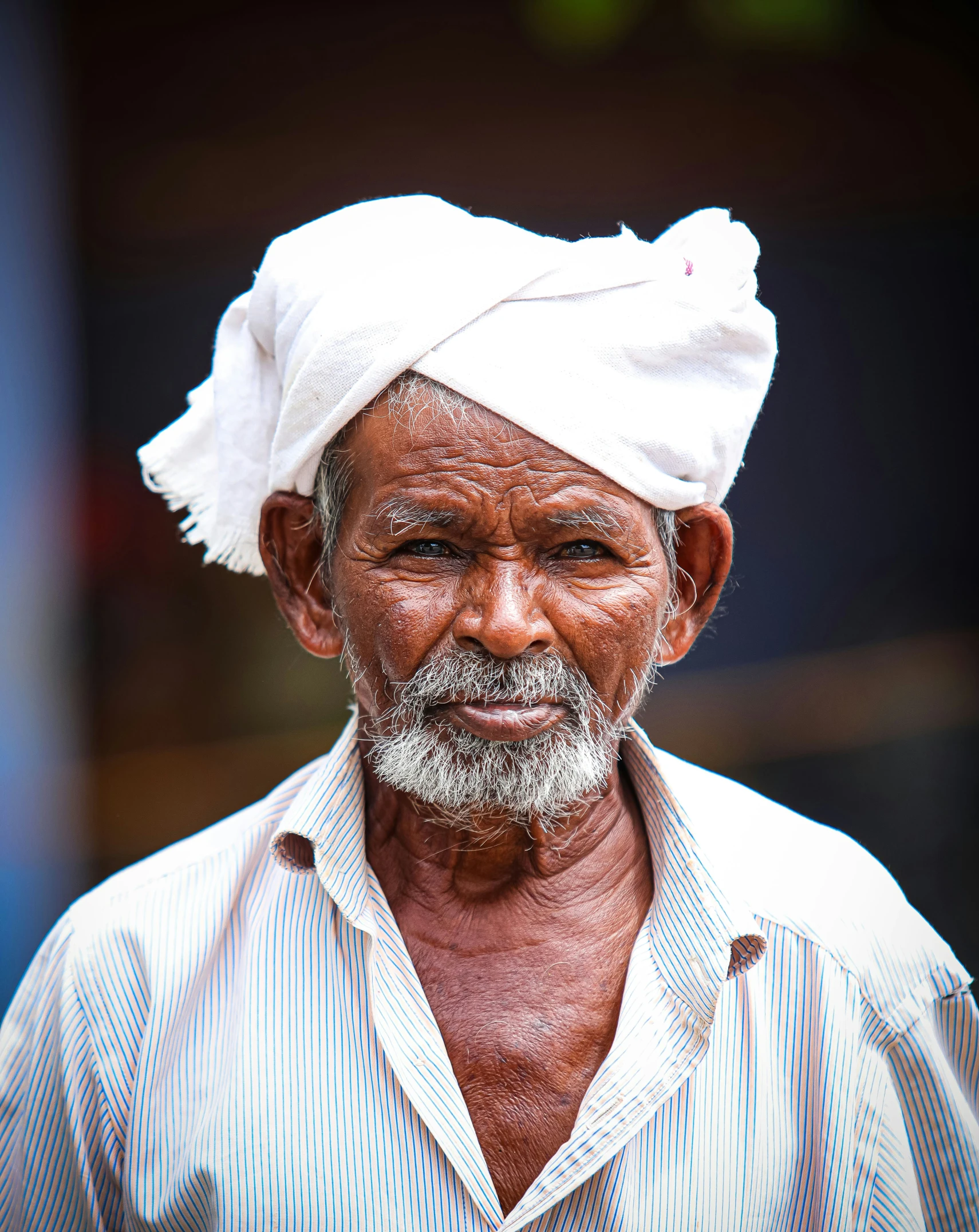 man wearing white headgear and blue shirt looking at camera